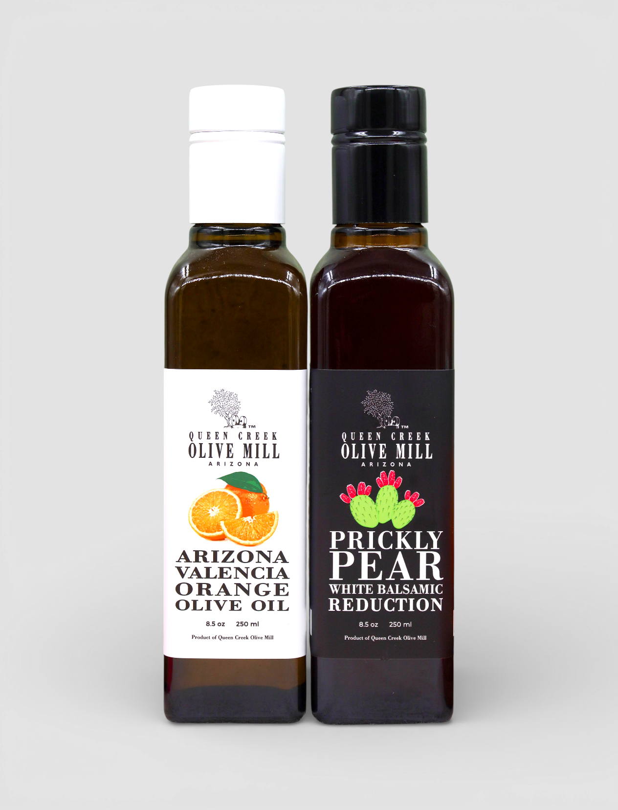 Two bottles of Queen Creek Olive Mill products on a light gray background